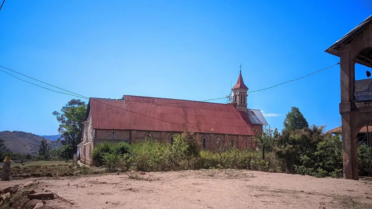 Église et maisons traditionnelles du village d'Ambohidrabiby sous un ciel bleu